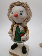 Christmas snowman wearing golden shimmer jacket holding holly sprig