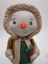 Christmas snowman wearing golden shimmer jacket holding holly sprig