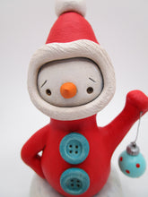 Christmas folk art Santa in red with ornament standing in snow