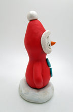 Christmas folk art Santa in red with ornament standing in snow