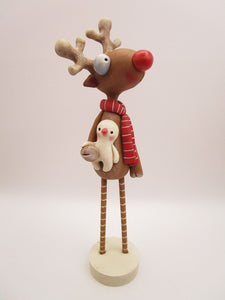 Christmas folk art reindeer with wood legs holding snowman