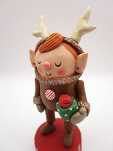 Christmas folk art elf in reindeer suit with little gift in hand