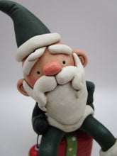Christmas folk art Santa sitting on a present