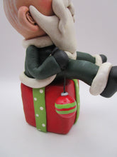 Christmas folk art Santa sitting on a present
