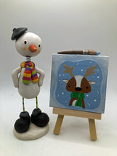 Christmas folk art artist snowman and his painting with brush and easel