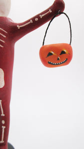 Halloween folk art spooky skeleton wearing a red bone costume with vintage style pumpkin - paper clay